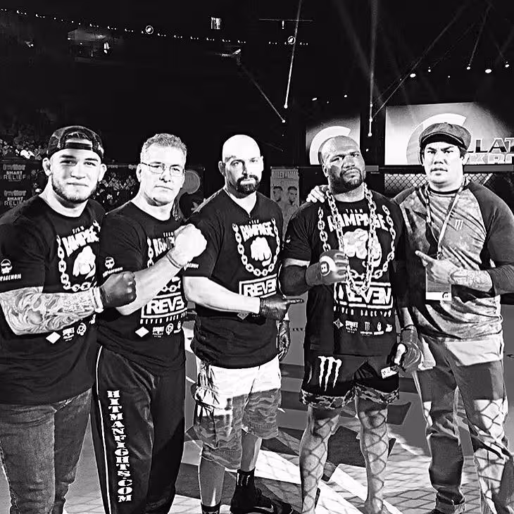 MMA fighters and coaches posing inside fight cage at live mixed martial arts event in black and white