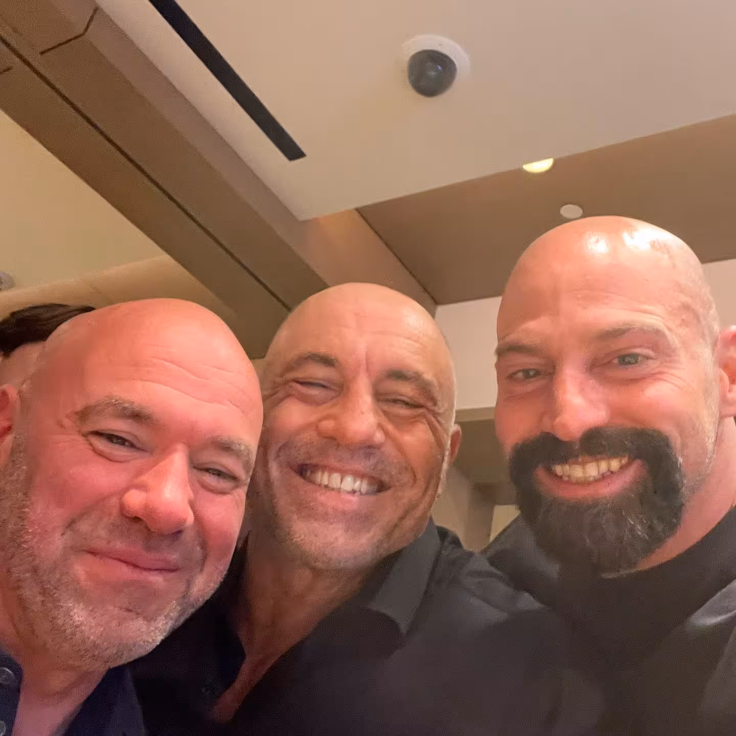 MMA personalities smiling for selfie indoors during combat sports event gathering